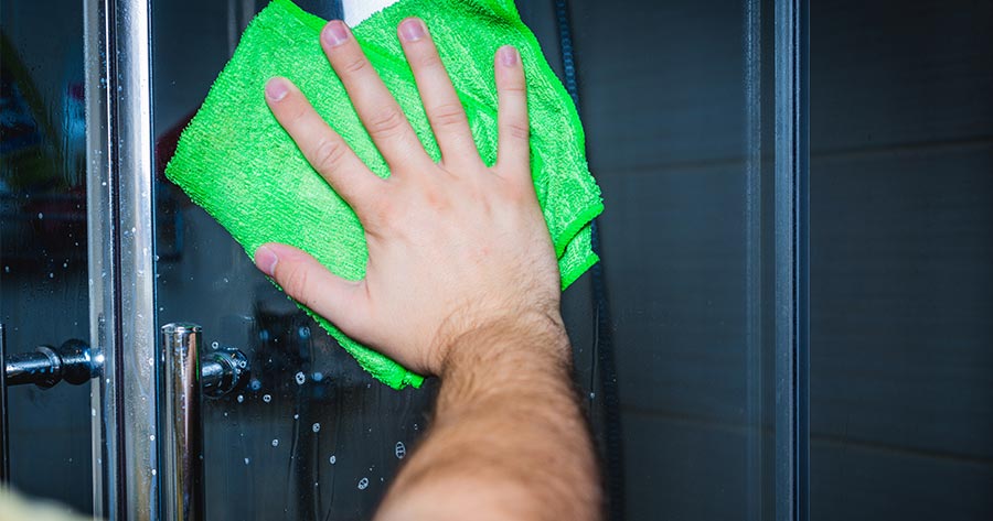 Hand cleaning shower glass with microfiber towel