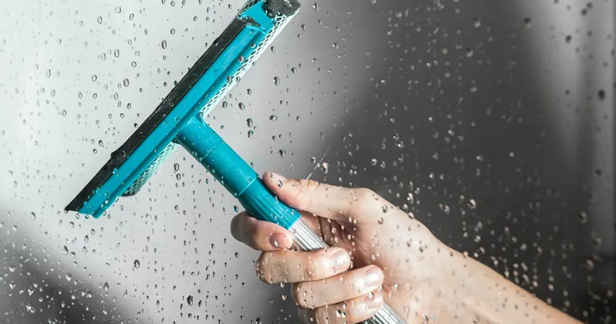Cleaning a glass shower door with a squeegee