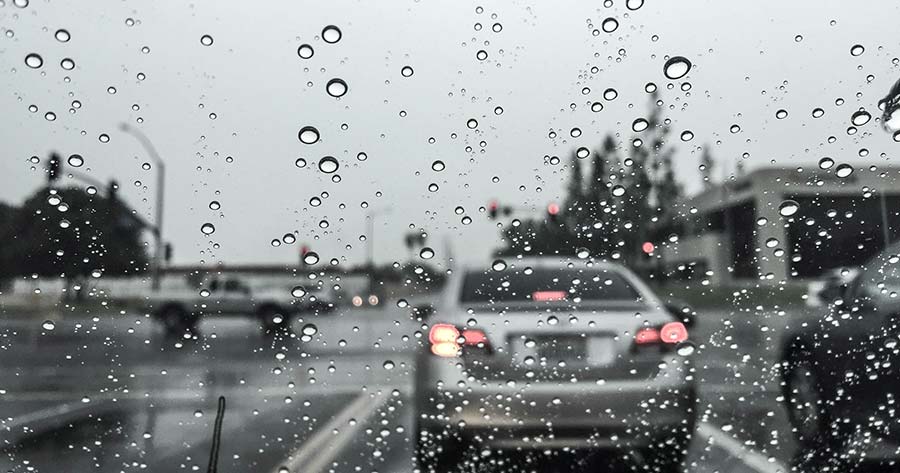 A car windshield with raindrops on it, treated with a car windshield rain repellent coating