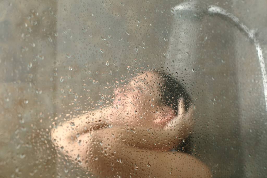An unfocused shoulders-up shot of a woman showering
