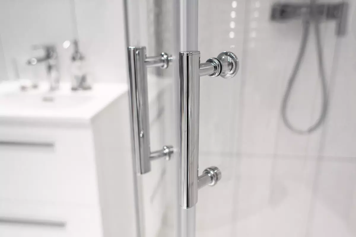 A close up on the metal handles of a clean glass shower door.